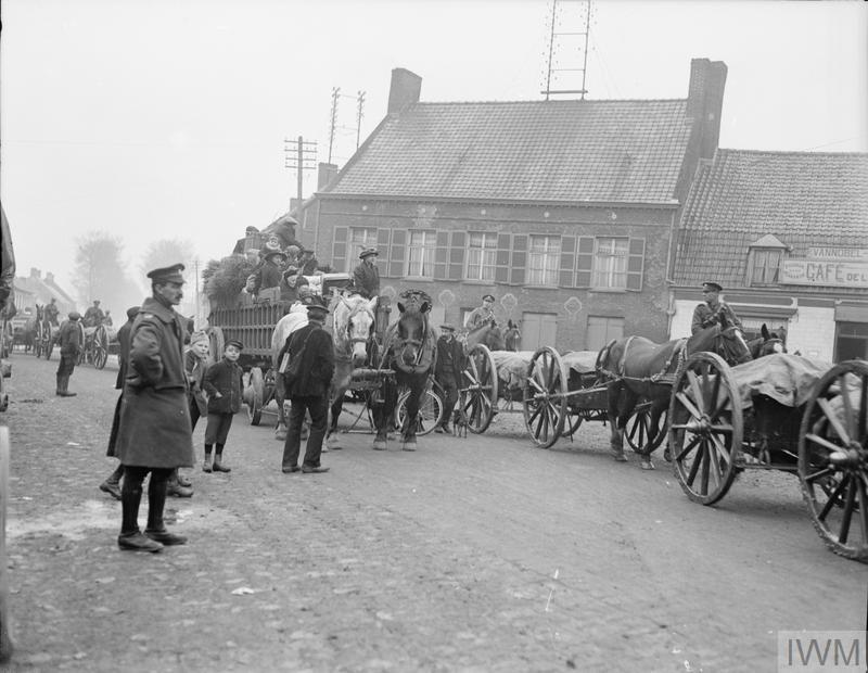 French refugees from Bailleul, Merris and Meteren in a farm-cart on their way to Cassel passing through Caestre. Note Royal Artillery limbers going in the same direction, 12 April 1918.